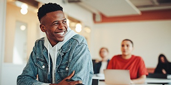 Teen in denim jacket smiling in classroom