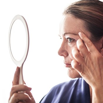 Woman looking at fine lines in mirror