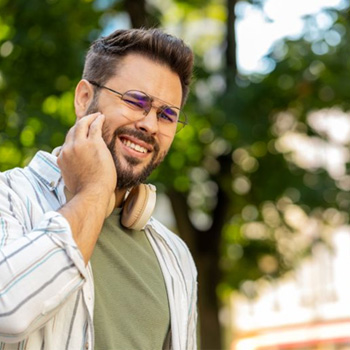 Man standing outside, suffering from a toothache