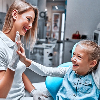 A dentist and young girl giving each other a high-five after a successful appointment