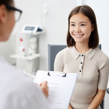 A female teen sitting upright while answering the dentist’s questions during an appointment