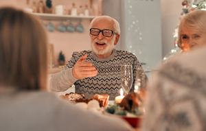 Senior man enjoying a meal and talking to family during the holidays